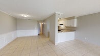 Located in Jacksonville, FL (32205), this single-floor residence offers a practical and well-appointed layout with consistent light-toned tile flooring running throughout every room. The open-concept living and dining area is a standout feature, providing a generous, flexible space accented by classic wainscoting along the lower walls and crown molding that adds a refined architectural touch. Large sliding glass doors flood the living area with natural light and open to outdoor views, creating a bright and welcoming atmosphere. Adjacent to the living space, the kitchen is defined by a peninsula counter that serves as both a workspace and a visual divider. White shaker-style cabinetry, granite countertops, a black electric range, a dishwasher, and a built-in range hood combine functionality with a clean, updated aesthetic. A hallway connects the main living areas to the private rooms, including bedrooms with tile flooring and direct access to the rest of the home. The bathroom features a full tub-shower combination with clean white surrounds. Textured ceilings are present throughout, and flush-mount lighting provides consistent illumination across the space. The overall ambiance is neutral, clean, and move-in ready, suitable for a variety of living arrangements.