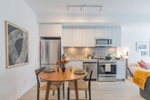 Located at 205 Queen St E in Brampton, Ontario, this thoughtfully designed one-bedroom, one-bathroom unit offers a clean, modern aesthetic with light-toned hardwood-style flooring and crisp white walls throughout. The open-concept layout connects the kitchen and living area seamlessly, maximizing the efficient use of space. The kitchen is outfitted with white flat-panel cabinetry extending to the ceiling, a grey tile backsplash, stainless steel appliances including a full-size refrigerator, and a double sink — all complemented by a dining area with room for a full table. The bright living room benefits from large sliding glass doors that open to a private balcony, flooding the space with natural light and offering open views of the surrounding Brampton cityscape. The bedroom continues the light-filled theme with its own floor-to-ceiling sliding door balcony access, roller blinds, and a dedicated walk-in closet. The bathroom features a clean, neutral palette with a vanity, framed mirror, and a stacked in-unit washer and dryer tucked neatly beside it. Throughout the unit, recessed lighting and modern fixtures contribute to the space's polished, contemporary ambiance.