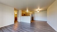 This well-appointed single-floor residence offers a thoughtfully designed open-concept layout that seamlessly connects the main living areas. The spacious living room features durable hardwood-style flooring and a ceiling fan, creating a comfortable and airy atmosphere. A set of large sliding glass doors floods the space with natural light and provides direct access to an outdoor patio overlooking a lush green landscape.

The kitchen is a standout feature, outfitted with stainless steel appliances including a refrigerator, electric range, and over-the-range microwave. Taupe shaker-style cabinetry pairs elegantly with granite-look countertops, and a breakfast bar with seating offers casual dining options. The kitchen flows naturally into the open living and dining areas, making it ideal for entertaining.

The bedroom is a well-sized, carpeted retreat equipped with its own ceiling fan for added comfort. The bathrooms are finished with the same cohesive design language — featuring taupe shaker cabinetry, granite countertops, large vanity mirrors, and hardwood-style flooring. One bathroom includes a walk-in shower, while the other provides ample storage with an overhead cabinet. Throughout the space, neutral tones and consistent finishes create a clean, modern, and inviting ambiance.