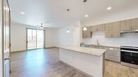 This 890-square-foot, single-story apartment at 3875 W Dobbins Rd in Laveen, Arizona offers a thoughtfully designed 2-bedroom, 2-bathroom layout. The open-concept kitchen and living area serves as the heart of the home, featuring a large granite-topped island with pendant lighting, modern wood-tone cabinetry, a white tile backsplash, and a full suite of stainless steel appliances including a refrigerator, range, and dishwasher. An in-unit washer is also conveniently located nearby. Light wood-look flooring runs throughout the main living areas, complementing the bright, neutral color palette. The primary bedroom includes a ceiling fan, a built-in desk with granite surface, and direct access to a private balcony via sliding glass doors. The primary bathroom offers a long granite vanity with a wood-tone cabinet, light wood flooring, and a glass-enclosed walk-in shower. The second bedroom features plush carpet, a ceiling fan, and windows that bring in natural light. Its adjacent bathroom includes an accessible roll-in shower with grab bars and a granite-topped vanity. A dedicated closet provides additional storage. The unit's clean, contemporary finishes and functional design make it a well-appointed living space.