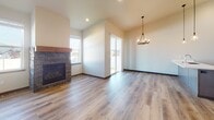 Located in Rathdrum, Idaho, this single-floor residence offers a thoughtfully designed layout with modern finishes throughout. The open-concept kitchen is a standout feature, boasting a large peninsula with a white quartz countertop, undermount sink, and contemporary pendant lighting — including an eye-catching wagon-wheel chandelier. Taupe cabinetry pairs with stainless steel appliances, including a refrigerator, range, and microwave. Light wood-look flooring flows through the main living and kitchen areas, creating a warm and cohesive aesthetic.

The hallway connects to multiple well-proportioned bedrooms, each featuring plush carpet flooring. One bedroom benefits from a large window that invites abundant natural light and views of the surrounding neighborhood. A spacious walk-in closet with wire shelving provides ample storage, complemented by additional sliding-door closets along the hallway.

The bathroom is cleanly appointed with a taupe vanity, white countertop, tub-shower combination, and wood-look flooring. A dedicated laundry area houses a full-size top-load washer and dryer with overhead wire shelving for added utility. The overall ambiance is clean, neutral, and move-in ready, suited for comfortable everyday living.