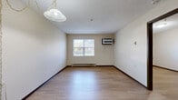 Located at 1356 Athena Lane in Zanesville, Ohio, this one-bedroom, one-bathroom unit offers a practical and efficiently designed single-floor layout. Light hardwood flooring runs throughout the main living areas, complementing the neutral cream-toned walls and textured ceilings that lend a clean, understated aesthetic.

The living room is an open, inviting space with a large window that draws in natural light and offers an outdoor view of the surrounding landscape. A wall-mounted HVAC unit and baseboard heating provide climate control, while a pendant light fixture adds a functional touch overhead.

The kitchen features warm wood cabinetry in an L-shaped configuration, complete with ample upper and lower storage, a full-size refrigerator, electric range, built-in microwave, and a countertop sink — all finished with durable laminate counters and matching hardwood flooring.

The bedroom is a comfortable, well-proportioned room with natural light provided by a window with blinds, baseboard heating, and the same hardwood flooring found throughout. Four closets across the unit offer generous storage options.

The bathroom includes a full soaking tub and shower combination with accessible grab bars, tile flooring, and a vanity with wood cabinetry. The unit is practical, move-in ready, and thoughtfully laid out to maximize every square foot of its cozy footprint.