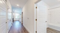 This single-floor unit offers a well-designed layout with a clean, modern aesthetic throughout. The open-concept kitchen serves as a central highlight, featuring white shaker cabinetry, granite countertops, a navy subway tile backsplash, a center island with pendant lighting, and stainless steel appliances including a refrigerator, range, microwave, and dishwasher. Natural light enters through multiple windows, creating a bright and inviting atmosphere.

Wood-look plank flooring runs throughout the main living areas and hallways, providing a cohesive and durable foundation. The living space is generously proportioned, with large corner windows that allow ample natural light and views of surrounding greenery. An additional living or flex area connects seamlessly via a hallway lined with paneled interior doors and gold-toned hardware.

The bedrooms are carpeted for comfort and each features a ceiling fan, natural light, and access to closets. The bathrooms are finished with wood-look flooring, white vanities with granite countertops, black hardware accents, and tub-shower combinations tiled in classic white subway tile. The overall design balances modern finishes with a clean, neutral palette throughout.