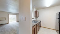 Located in Fargo, ND, this one-bedroom, one-bathroom unit offers a well-organized, single-floor layout designed for comfortable everyday living. The open living room features plush carpeting, baseboard heating, and a sliding glass door that floods the space with natural light and leads to a private balcony with outdoor views. A pass-through window connects the living area to the kitchen, which is equipped with warm wood cabinetry, laminate countertops, a double-basin sink, a dishwasher, and a full-size refrigerator, all set on easy-care hard flooring. The bedroom is a generous, carpeted retreat with a large window fitted with blinds for natural light and privacy, along with baseboard heating. It provides direct access to a spacious walk-in closet outfitted with wire shelving and hanging rods on multiple walls, offering ample storage. The full bathroom features tile flooring, a wood vanity with a large mirror and lighted fixtures, and a shower-tub combination. A dedicated in-unit laundry area houses a full-size washer and dryer with overhead wire shelving. Textured ceilings and warm wood trim carry throughout, giving the space a cohesive, residential feel.
