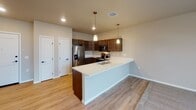 Located on 26th Street South in Fargo, North Dakota, this single-floor residence offers a thoughtfully designed open-concept layout with contemporary finishes throughout. The kitchen serves as a central highlight, featuring rich dark cabinetry, crisp white countertops, a peninsula with an undermount sink, stainless steel appliances including a refrigerator with ice maker, range, and microwave, and light hardwood-style flooring. Pendant lighting above the peninsula adds a polished touch, while recessed lighting illuminates the overall space. The kitchen flows seamlessly into the carpeted living area, which benefits from natural light through a large window and direct access to an outdoor balcony through a glass-panel door. Neutral wall tones create a consistent, calming palette across all rooms. The bathroom is notably spacious, offering a long dark-wood double vanity with a white countertop, dual mirrors with bar lighting, a soaking tub, and hardwood-style flooring extending the length of the room. A walk-in closet provides generous storage with wire shelving and hardwood-style flooring. Additional rooms feature plush carpet and neutral walls, offering versatile living spaces.