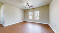 This single-story, 2-bedroom, 2-bathroom home offers a thoughtfully designed open-concept layout that maximizes its comfortable footprint. The living area features warm wood-style flooring and vaulted ceilings, creating a bright and airy atmosphere. French doors with sidelights invite natural light into the space while providing access to the exterior. The kitchen is a functional centerpiece, showcasing rich dark cabinetry, granite countertops, stainless steel appliances — including a refrigerator, range, microwave, and dishwasher — and a peninsula that opens to the living and dining area, ideal for everyday use and entertaining. A pendant light fixture adds a finishing touch above the dining space. Both bedrooms offer plush carpet flooring and natural light from windows with blinds. The primary bedroom features a ceiling fan and two windows offering neighborhood views. The second bedroom is equally well-lit with carpeted flooring. Both bathrooms mirror the kitchen's design aesthetic with dark cabinetry, granite countertops, wood-style flooring, and tiled tub-shower combinations. The consistent use of neutral tones, granite surfaces, and warm wood-style flooring throughout creates a cohesive and inviting ambiance across the entire home.
