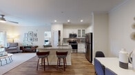 Located at 2700 Whakatane in Fuquay-Varina, NC, this single-floor residence offers a thoughtfully designed layout with modern finishes and a bright, welcoming ambiance. The open-concept kitchen is a standout feature, boasting white shaker cabinetry with glass-front upper panels, granite countertops, a tile backsplash, and a full suite of stainless steel appliances including a range, microwave, and refrigerator. A peninsula with seating provides a casual dining option and connects the kitchen to the living areas. The dedicated dining area accommodates a full-sized table and is accented by crown molding and rich hardwood-style flooring. The living room is generously proportioned, featuring crown molding, a ceiling fan, and French doors that invite natural light and outdoor access. The bedroom offers plush carpeting, a ceiling fan, and dual closets providing ample storage. The bathroom is well-appointed with granite countertops, white cabinetry, hardwood-style flooring, and a full tub-shower combination. A dedicated in-unit laundry room includes a full-size washer and dryer with overhead shelving. Throughout the space, neutral tones, recessed lighting, and consistent finishes create a cohesive and comfortable living environment.