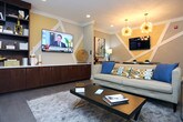 Located on Juniper Street NE in Atlanta's vibrant Old Fourth Ward neighborhood, this single-floor amenity lounge is thoughtfully designed to offer a variety of social and functional spaces within one open, interconnected layout. The space is unified by wood-look plank flooring, recessed lighting, and a contemporary color palette of warm grays, cream, and mustard yellow accents that carry throughout.

Upon entry through black steel-framed glass doors, a welcoming lounge area greets visitors with a plush sofa, tufted leather armchairs, area rugs, and a wall-mounted television set against a decorative geometric accent wall. This flows seamlessly into a central game room anchored by a full-size pool table and a shuffleboard table, creating a lively social hub.

A prominent bar-style island with a white countertop and pendant globe lighting serves as a coffee and refreshment station, complete with a Starbucks coffee setup, stainless appliances, beverage refrigerators, and a mosaic tile backsplash. A private conference room off the main area features a Sputnik chandelier, a dark wood conference table, and a wall-mounted display screen for meetings or presentations. Large windows throughout bring in natural light, enhancing the open, community-oriented ambiance.