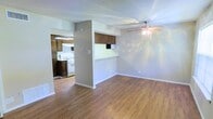 This single-floor residence offers a practical and comfortable layout designed for everyday living. The main living area features warm hardwood-style flooring that extends throughout the space, complemented by a ceiling fan that provides both functionality and a finishing touch to the room. Neutral-toned walls create a clean, versatile backdrop suitable for a variety of interior styles.

A defining feature of this space is the open connection between the living area and the kitchen, facilitated by a pass-through counter with an overhead cabinet. This design element enhances the sense of openness while maintaining a defined boundary between the two areas. The kitchen is equipped with dark wood cabinetry, a white gas range, and a range hood, offering a functional cooking environment. Additional upper and lower cabinetry provides ample storage space.

The textured ceiling adds subtle character throughout the unit. The layout is efficient and well-organized, making good use of the available floor space. Overall, the residence presents a straightforward, functional living environment with cohesive finishes and a welcoming ambiance suited to comfortable day-to-day living.