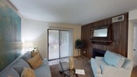 Located at 1651 Knollwood Dr in Mobile, Alabama, this single-story home offers a comfortable and functional layout designed for easy living. The living room serves as the heart of the home, showcasing a distinctive wood-paneled accent wall that frames a classic fireplace, adding warmth and character to the space. A sliding glass door flanked by vertical blinds floods the room with natural light while providing a seamless connection to the outdoor area, offering views of the surrounding greenery. The living room is generously sized, accommodating a relaxed seating arrangement centered around a glass-top coffee table, creating an inviting atmosphere for both everyday living and entertaining. The neutral wall tones complement the warm wood tones of the fireplace surround, creating a cohesive and welcoming ambiance throughout. The single-floor layout ensures convenient accessibility, making the home practical and easy to navigate. Overall, this property combines classic design elements with functional living spaces, offering a comfortable retreat in an established Mobile neighborhood.