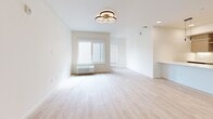 Located at 4001 198th St SW in Lynnwood, WA, this 2-bedroom, 2-bathroom unit offers a well-designed single-floor layout with a cohesive modern aesthetic. Light wood-tone flooring runs throughout, creating a warm, continuous feel across all rooms.

The open-concept kitchen and living area form the heart of the unit. The kitchen is outfitted with flat-front cabinetry in a natural wood finish, white quartz countertops, a peninsula for additional prep or seating space, and stainless steel appliances including a refrigerator, range, and over-the-range microwave. Under-cabinet lighting adds a refined touch. The adjoining living room is bright and airy, featuring a contemporary multi-ring ceiling light fixture and windows that invite natural light.

Both bedrooms are well-proportioned with clean white walls, light flooring, and large windows offering views of the surrounding community. Each bedroom includes dedicated closet space. The primary bedroom benefits from its own private bathroom access.

The two bathrooms maintain the unit's clean design language — one features a full soaking tub and shower combo with white subway tile surround and brushed nickel fixtures, while the second is a well-appointed full bath with a modern vanity, white countertop, and wood-toned cabinetry. Both bathrooms include accessibility grab bars.