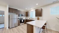 This two-story home offers a thoughtfully designed layout across two floors, combining modern finishes with functional living spaces. The ground floor is anchored by a contemporary kitchen featuring rich dark-wood cabinetry, stainless steel appliances, a white quartz peninsula with bar seating, and light hardwood flooring. The open living area connects seamlessly to the kitchen and staircase, bathed in recessed lighting and a clean, neutral palette. A dedicated laundry room with side-by-side washer and dryer, plus wire shelving, adds everyday convenience, while the attached garage houses a water heater and offers additional utility space.

Upstairs, the primary bedroom provides a comfortable retreat, accompanied by two additional bedrooms with plush carpeting and bright windows. A dedicated office with a walk-in closet offers flexible space for work or study. Three full bathrooms are distributed across the home, each featuring wood-tone vanities, white quartz countertops, and tub-shower combinations. Multiple closets throughout the upper level ensure ample storage. The home's consistent use of light tones, recessed lighting, and quality materials creates a clean, modern ambiance suited for everyday living.