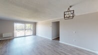Located at 366 Schraffts Dr in Waterbury, Connecticut, this single-floor unit offers a well-organized layout with a variety of updated finishes throughout. The open living and dining area is a standout feature, showcasing light-toned hardwood-style flooring, neutral gray walls, and a textured ceiling. A stylish geometric pendant light fixture anchors the dining space, while sliding glass doors lead out to a private balcony, flooding the room with natural light and offering outdoor views of surrounding greenery. A decorative column separates the entry corridor from the main living area, adding a subtle architectural touch. The kitchen is thoughtfully appointed with white shaker-style cabinetry, granite-look countertops, tile flooring, and black appliances including a range, dishwasher, and over-the-range microwave. The bedrooms are carpeted for comfort, each featuring neutral tones, baseboard heating, and natural light from windows. One bedroom includes a walk-in closet and direct access to the bathroom, providing added convenience. The bathroom features a vanity with a single-basin sink and a mirror cabinet. Baseboard heating is present throughout the unit, ensuring consistent warmth across all rooms.