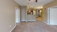 This single-floor residence features a thoughtfully designed open-concept layout connecting the living area to the kitchen. The living space is finished with neutral-toned carpet and ceiling fans with integrated lighting, creating a comfortable atmosphere. A sliding glass door leads to an outdoor balcony, allowing natural light to fill the room.

The kitchen is equipped with stainless steel appliances, including a refrigerator, electric range, and built-in microwave. Warm-toned wood cabinetry pairs with granite-style countertops, and the kitchen island provides a functional breakfast bar. Hardwood-style flooring extends throughout the kitchen and bathrooms.

The bedrooms feature plush carpet, neutral walls, and windows with blinds that bring in natural light. Ceiling fans are present in multiple rooms for added comfort.

The bathrooms are finished with rich wood vanity cabinetry, granite countertops, and large mirrors. One bathroom includes a walk-in shower with a frosted glass door and chrome frame. A hallway with multiple closet doors provides ample storage. The overall palette of warm beige tones and consistent finishes lends the space a cohesive, functional character.