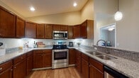 This single-floor residence at 4464 Professional Parkway in Groveport, Ohio offers a thoughtfully designed layout with comfortable living spaces and quality finishes throughout. The kitchen serves as a functional centerpiece, featuring rich medium-toned wood cabinetry, granite countertops, stainless steel appliances including a range and built-in microwave, under-cabinet lighting, and hardwood-style flooring. Vaulted ceilings in the kitchen add an open, airy feel to the space.

Adjacent to the kitchen, the dining area accommodates a full-sized table beneath a chandelier, with hardwood-style flooring continuing seamlessly from the kitchen. The living room provides a warm, relaxed atmosphere with the same flooring, a ceiling fan, and a window offering natural light.

The primary bedroom features a tray ceiling, ceiling fan, plush carpeting, and a generous walk-in closet with dual wire shelving systems. An additional bedroom also offers carpeted flooring, a ceiling fan, and multiple windows allowing ample natural light. The bathroom is well-equipped with a granite vanity, wood-style flooring, and a full tub-shower combination.

A dedicated laundry room includes granite-topped cabinetry and a full-sized washer and dryer, completing this well-rounded and practical residence.