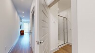 Located at 1001 16th Ave S in Nashville's iconic Music Row neighborhood, this efficiently designed single-floor unit makes excellent use of its compact footprint. The open-concept layout seamlessly connects the kitchen and living areas, creating a cohesive and functional living space.

The kitchen is a standout feature, outfitted with stainless steel appliances including a full-size refrigerator with ice maker, electric range, and built-in microwave. Two-toned cabinetry combines soft gray lower cabinets with light wood-grain upper cabinets, complemented by a white herringbone tile backsplash and clean white countertops. A high-top wooden island with barstool seating adds a casual dining element.

The living area is bright and airy, anchored by large sliding glass doors with vertical blinds that invite abundant natural light and provide outdoor access. A ceiling fan, wall-mounted television, built-in wooden shelving, and a space-saving Murphy bed configuration maximize versatility in this area.

The bathroom features warm wood-look flooring, crisp white walls, and a glass-enclosed walk-in shower with elegant marble-style tile surround. Recessed lighting and clean finishes carry throughout the unit, maintaining a modern and cohesive aesthetic. Light wood-look flooring unifies all areas of the space.
