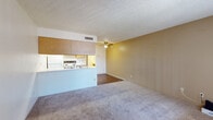 Located at 160 N Pantano Rd in Tucson, Arizona, this single-floor unit offers a functional and straightforward layout designed for comfortable everyday living. The open-concept living and dining area is finished with wall-to-wall carpet and features a ceiling fan with light fixture, a textured ceiling, and warm neutral-toned walls that create an inviting atmosphere. A peninsula-style kitchen connects seamlessly to the living space and is equipped with wood-toned cabinetry, a white refrigerator, electric range, dishwasher, and a double sink — all set above durable wood-look flooring. A dedicated bedroom features sliding glass doors that open directly to a private outdoor patio, allowing for natural light and easy outdoor access. A second room with a large window provides additional flexible living space. The bathroom includes a wide vanity with oak cabinetry, generous countertop space, a large wall mirror, and louvered closet doors visible in the reflection. Throughout the unit, a consistent design palette of warm neutrals, wood accents, and practical finishes creates a cohesive and livable environment well-suited for Tucson's desert setting.
