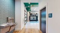 Located at 112 Point Place in Mooresville, NC, this dedicated fitness center offers a thoughtfully designed exercise space across a single floor. The interior is defined by striking tray ceilings accented in a bold teal color, recessed linear lighting, and large ceiling fans that contribute to a bright and energetic atmosphere. Light wood-look flooring and neutral carpet zones divide the space functionally, providing both comfort and practicality underfoot.

The exercise room is generously proportioned and comprehensively outfitted. A full array of cardio equipment, including multiple treadmills and a stationary bike, lines one side of the room alongside windows fitted with slatted blinds that allow natural light while maintaining privacy. The strength training area features a well-stocked freeweight selection with dumbbells and kettlebells, medicine balls, stability balls, a heavy punching bag, and a variety of cable and resistance machines. Wall-mounted mirrors enhance the sense of openness and allow users to monitor their form throughout their workout. Mounted flat-screen televisions add an entertainment element to the cardio zone.

A standout architectural feature is the full-height glass panel garage door that opens directly to an outdoor turf training area, seamlessly connecting the indoor and outdoor fitness environments. A separate adjoining room provides additional space for more focused or private training sessions, completing this versatile and modern fitness facility.