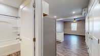 Located at 24 Eighth St N in Fargo, North Dakota, this studio offers a thoughtfully designed single-floor layout that makes efficient use of its space. Rich, dark hardwood-style flooring runs throughout the unit, lending warmth and continuity to the open floor plan.

The kitchen is a standout feature, outfitted with crisp white shaker-style cabinetry, granite countertops, and a full suite of stainless steel appliances including a refrigerator, range, microwave, and dishwasher. An L-shaped counter configuration provides ample workspace and storage, while recessed lighting illuminates the area effectively.

The main living area is open and airy, benefiting from natural light through a window with blinds and a ceiling fan overhead that adds both comfort and ambiance. A wall-mounted mini-split unit provides climate control. Generous closet space is provided by double white panel doors along one wall, offering practical storage solutions.

The bathroom features a full tub and shower combo with a built-in surround shelf system, finished in clean, neutral tones. Overall, the unit presents a modern, move-in-ready aesthetic with clean lines, neutral walls, and functional design elements throughout.
