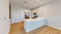 Located at 102 Kennedy Ridge Way in Mooresville, NC, this well-designed one-bedroom, one-bathroom home offers a clean, modern aesthetic across a single floor. Light wood-style flooring flows consistently throughout, complementing the neutral gray-toned walls and crisp white trim that define the interior.

The open-concept kitchen and living area serves as the heart of the home. The kitchen features white shaker-style cabinetry reaching toward the ceiling, a white quartz peninsula with an undermount sink, stainless steel appliances including a French door refrigerator, built-in microwave, and range, as well as a subway tile backsplash and recessed lighting. The adjacent living area benefits from a ceiling fan and a glazed entry door with transom window that invites ample natural light.

The bedroom is a well-proportioned, bright space with two windows overlooking the outdoors, filling the room with natural light. A dedicated closet and a connecting hallway provide practical storage and circulation.

The bathroom is finished with white subway tile surrounding a full soaking tub and shower combination, brushed nickel fixtures and grab bar, a white vanity with clean countertop, and the same wood-style flooring carried throughout. A dedicated laundry area with a built-in shelf is also integrated into the layout, adding everyday convenience to this thoughtfully designed home.