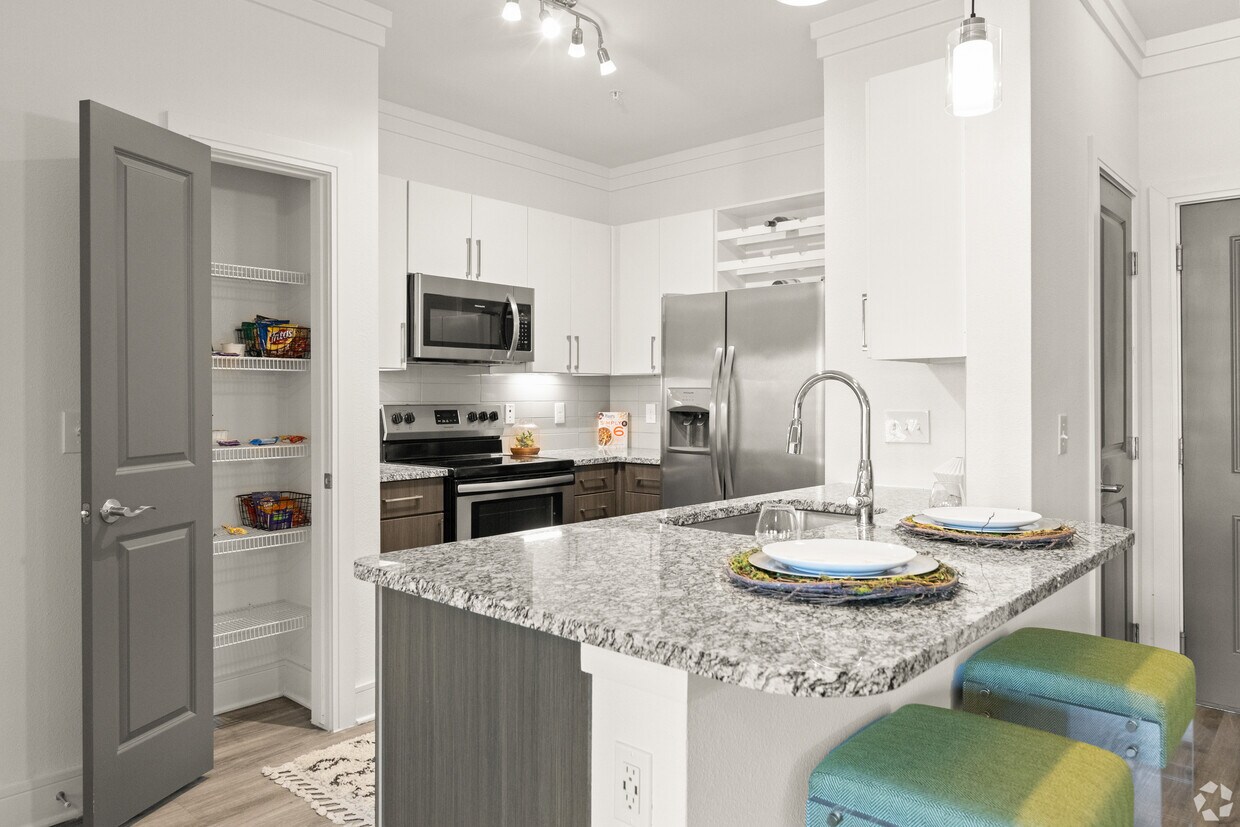 Cocina con gabinetes blancos y espresso, encimeras de granito moteado, electrodomésticos de acero inoxidable y pisos de superficie dura. - Avalon Frisco