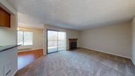 Located at 1782 D St in Hayward, California, this single-floor residence offers a well-organized layout with a variety of functional living spaces. The living room serves as the heart of the home, featuring plush wall-to-wall carpeting, a textured ceiling, and a tile-surround fireplace with a wood mantel. A large sliding glass door floods the room with natural light and provides direct access to the outdoors, complemented by vertical blinds for privacy. Adjacent to the living area, the galley-style kitchen is equipped with warm oak cabinetry, dark granite countertops, a skylight-style ceiling panel that brightens the space, and hardwood flooring. A white range, microwave, and refrigerator complete the functional setup. The bedrooms are carpeted and receive abundant natural light through well-placed windows, with mirrored sliding closet doors adding both storage and a sense of spaciousness. The bathroom features hardwood flooring, a granite-topped vanity with an undermount sink, a large wall mirror, and a tub-shower combination enclosed by sliding glass doors. Throughout the home, a consistent neutral color palette and practical finishes create a clean, cohesive ambiance suitable for comfortable everyday living.