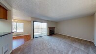 Located at 1782 D St in Hayward, California, this single-floor residence offers a well-organized layout with a variety of functional living spaces. The living room serves as the heart of the home, featuring plush wall-to-wall carpeting, a textured ceiling, and a tile-surround fireplace with a wood mantel. A large sliding glass door floods the room with natural light and provides direct access to the outdoors, complemented by vertical blinds for privacy. Adjacent to the living area, the galley-style kitchen is equipped with warm oak cabinetry, dark granite countertops, a skylight-style ceiling panel that brightens the space, and hardwood flooring. A white range, microwave, and refrigerator complete the functional setup. The bedrooms are carpeted and receive abundant natural light through well-placed windows, with mirrored sliding closet doors adding both storage and a sense of spaciousness. The bathroom features hardwood flooring, a granite-topped vanity with an undermount sink, a large wall mirror, and a tub-shower combination enclosed by sliding glass doors. Throughout the home, a consistent neutral color palette and practical finishes create a clean, cohesive ambiance suitable for comfortable everyday living.