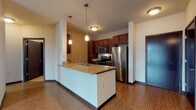 Located at 1300 S Barker Rd in Brookfield, Wisconsin, this single-floor residence offers a thoughtfully designed layout with a clean, contemporary aesthetic throughout. The open-concept living and dining area is anchored by warm hardwood-style flooring and neutral walls, creating a bright and welcoming atmosphere. A large sliding glass door floods the living space with natural light and provides views of the surrounding exterior.

The kitchen is a standout feature, boasting rich dark wood cabinetry, granite countertops, and a full suite of stainless steel appliances including a refrigerator, range, and built-in microwave. A peninsula with pendant lighting above serves as both a prep space and a casual dining area, seamlessly connecting the kitchen to the main living space.

The bedrooms are carpeted for comfort, each offering a quiet, neutral environment with natural light provided by window blinds. Dark-stained interior doors add a refined contrast to the light-toned walls throughout.

The bathroom is well-equipped with granite countertops, dark wood cabinetry, and a walk-in shower. Conveniently situated nearby is an in-unit laundry area with a full-size washer and dryer. The overall design balances modern finishes with practical functionality, making this a comfortable and move-in-ready space.