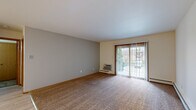 This single-floor, one-bedroom, one-bathroom residence offers a straightforward and functional layout across a well-utilized footprint. The space is organized around a central hallway that connects the key living areas, providing easy flow throughout.

The living room is the largest common area, featuring neutral-toned carpet, a sliding glass door that brings in natural light and outdoor views, and a wall-mounted air conditioning unit alongside baseboard heating. The open-plan arrangement incorporates a designated dining area adjacent to the kitchen, which is equipped with light hardwood-style flooring, dark cabinetry with upper storage, and standard white appliances including a refrigerator and range.

The bedroom is a comfortable, well-proportioned room finished with plush carpet and neutral walls. A window with blinds allows natural light to filter in while maintaining privacy, and baseboard heating ensures year-round comfort. Closet access is conveniently integrated.

The bathroom features tile flooring, a single-sink vanity with a laminate countertop and wood cabinetry, a mirrored medicine cabinet, and a full shower/tub combination. Throughout the residence, light hardwood-style flooring transitions to carpet in the living and sleeping areas, providing both practicality and warmth. The overall aesthetic is clean, neutral, and move-in ready.