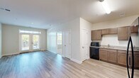 Located at 400 Katrina Court in Midlothian, VA, this 2-bedroom, 2-bathroom residence offers a thoughtfully designed single-floor layout that maximizes comfort and functionality. The open-concept living area is finished with light-toned wood-style flooring that flows seamlessly throughout the main spaces, creating a bright and cohesive aesthetic. Large windows and glass French doors in the living room invite abundant natural light and provide access to an outdoor balcony with views of the surrounding area. The kitchen features warm-toned cabinetry, light stone-look countertops, and black appliances including a refrigerator, range, dishwasher, and microwave, all arranged in an efficient L-shaped configuration. Both bedrooms are carpeted for added comfort, with large windows that bring in natural light. The primary bedroom offers a generous footprint and convenient closet access. A connecting hallway links the bedrooms and bathrooms, maintaining a practical flow throughout the unit. The bathrooms are finished with clean white subway tile surrounds in the tub/shower areas, contributing to a crisp, modern feel. Neutral wall tones and white trim throughout the residence create a versatile canvas suitable for a variety of interior styles.