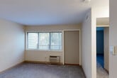 Located at 115 N Main St in Bellingham, MA, this one-bedroom, one-bathroom unit is thoughtfully laid out across a single floor. The living and dining areas are carpet-floored and bathed in natural light through wide, blinds-fitted windows, with a wall-mounted HVAC unit providing climate control and a door opening directly to the balcony. The balcony offers a peaceful wooded view, with mature trees and open green space providing a serene natural backdrop. The kitchen features warm honey-toned wood cabinetry, ample upper and lower storage, a double-basin sink, and tile flooring, with a full-size refrigerator and range included. Flanked by closets on either side, the kitchen hallway offers convenient additional storage. The bedroom is generously proportioned, finished with soft carpet, neutral walls, and a wide window for natural light. A set of double-door closets provides substantial built-in storage. The bathroom is clean and functional, featuring a full soaking tub with shower and white surround. Three closets throughout the unit, plus a dedicated utility room, ensure plentiful storage. A hallway connects all areas efficiently, completing this well-organized and comfortable single-level home.