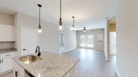 Located at 6080 Tides Way in Myrtle Beach, SC, this single-floor home offers a well-designed, open-concept layout that seamlessly connects the kitchen, dining, and living areas. The kitchen is a standout feature, boasting granite countertops, crisp white cabinetry with sleek dark hardware, a subway tile backsplash, stainless steel appliances including a refrigerator, microwave, and range, and a central island with an undermount sink. Stylish pendant lighting illuminates the island and the adjoining living space, which is finished with light hardwood-style flooring and ceiling fans throughout. French doors in the living area lead to an outdoor space, inviting natural light and fresh air inside. The bedrooms feature neutral-toned carpet, ceiling fans, and windows with blinds that provide natural light and outdoor views. A spacious walk-in closet with wire shelving offers generous storage. The bathrooms are finished with granite-topped white vanities and hardwood-style flooring; one bathroom includes a full tub-shower combination. Neutral wall tones, consistent trim details, and quality finishes throughout give this home a clean, modern aesthetic well-suited to the coastal Myrtle Beach lifestyle.