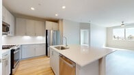Located on East Camelback Road in Phoenix, Arizona, this well-appointed 2-bedroom, 2-bathroom residence offers a thoughtfully designed single-level layout with a clean, modern aesthetic throughout. The open-concept kitchen and living area serves as the heart of the home, featuring a large center island with a quartz countertop, stainless steel appliances including a refrigerator, dishwasher, gas range, and microwave, as well as soft gray cabinetry and light wood flooring that extends throughout the main living spaces. A pantry closet provides generous storage directly off the kitchen. The primary bedroom is a spacious retreat finished with plush carpet and ceiling fan, while the second bedroom offers light wood flooring and large windows framing views of palm trees and the surrounding Phoenix cityscape. Each bathroom is finished with modern vanities featuring white quartz countertops and wood-tone flooring. The primary bath includes direct access to a walk-in closet with built-in shelving, while the second bath offers a full soaking tub with tiled shower surround. A dedicated in-unit laundry room with side-by-side washer and dryer adds everyday convenience. The space combines functional design with contemporary finishes throughout.