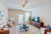 This single-story residence in Crestview, Florida offers a well-designed layout with a cohesive, neutral color palette throughout. The spacious living room serves as the heart of the home, featuring plush carpeted flooring, a ceiling fan with light fixture, and natural light streaming through windows with white curtains and blinds. A private entry door adds convenience directly from this area.

The open-concept dining area flows seamlessly from the living room and sits adjacent to the kitchen, which is separated by a granite-topped breakfast bar. The kitchen is equipped with dark cabinetry, granite countertops, black appliances including a range, over-the-range microwave, and refrigerator, all set atop durable tile flooring with a stone-like finish.

The dining space features track lighting overhead and direct sightlines to the kitchen, creating an effortlessly connected entertaining area. A built-in desk with granite countertop and wood cabinetry is tucked conveniently near the bedroom, offering a functional workspace.

The bedroom is generously sized with plush carpet, a ceiling fan, and ample natural light from a large window. The bathroom features tile flooring, a tub-shower combination, a wood vanity with granite countertop, and a large mirror, providing practical and comfortable amenities throughout.