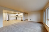Located at 7932 Beverly Ln in Everett, WA, this generously sized single-floor unit offers six bedrooms, two bathrooms, and a well-organized layout designed for comfortable group living. The open-concept living room is expansive, featuring plush carpeting and large windows with a sliding glass door that frame lush views of the surrounding evergreen trees, filling the space with natural light. The kitchen is seamlessly integrated into the living area and is outfitted with white cabinetry, stainless steel appliances including a refrigerator, range, microwave, and dishwasher, along with light hardwood-style flooring that extends through the entry and kitchen zones. The six bedrooms are carpeted and bright, each featuring windows with scenic outdoor views of the Pacific Northwest landscape. The spacious primary bedroom includes a walk-in closet with built-in wire shelving for ample storage. Both bathrooms feature light wood-style flooring, wide vanities with generous counter space, large mirrors, and clean, neutral finishes. A dedicated in-unit laundry room houses a full-size Whirlpool washer and dryer. Two hallways connect the rooms efficiently, and an additional closet provides supplemental storage throughout this functional and well-appointed home.