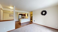 Located at 20917 44th Ave W in Lynnwood, Washington, this single-floor residence offers a well-designed layout that balances open communal spaces with comfortable private areas. The open-concept living and dining area features plush carpeting that transitions seamlessly into wood-style laminate flooring in the kitchen and dining zone, creating a clear yet flowing distinction between spaces. A half-wall peninsula separates the kitchen from the main living area, providing both a casual dining surface and an architectural element that maintains an open, airy feel. The kitchen is equipped with stainless steel appliances, including a refrigerator, microwave, and range, complemented by dark cabinetry and recessed lighting overhead. A hallway leads to multiple bedrooms, each finished with soft carpeting, neutral walls, and warm wood-toned door and baseboard trim. The bedrooms benefit from natural light through sizable windows fitted with blinds. One bedroom features a spacious walk-in closet. The bathroom is finished with tile flooring, a single-sink vanity with dark cabinetry, a wall mirror, and a full soaking tub with shower. Throughout the residence, consistent neutral tones, warm wood accents, and clean lines create a cohesive and functional living environment.