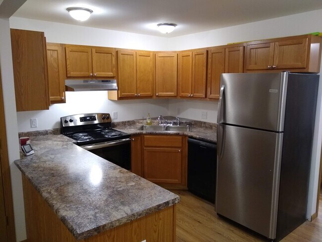 Cocina con electrodomésticos de acero inoxidable y gabinetes de roble Amish. - Crown Pointe Townhomes - Shiloh