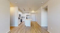 This well-appointed single-floor residence offers a thoughtfully designed open-concept layout that seamlessly connects the kitchen, dining, and living areas. The kitchen is a standout feature, showcasing crisp white shaker-style cabinetry with matte black hardware, a classic subway tile backsplash, light quartz countertops, and a full suite of stainless steel appliances including a range, microwave, and French door refrigerator. A central island provides additional prep space and casual seating. Pendant lighting and track lighting add warmth and functionality to the kitchen area. Light wood-look flooring flows throughout the main living spaces, complementing the neutral, warm-toned walls and creating a bright, cohesive aesthetic. The living area features a ceiling fan and is filled with natural light from windows overlooking a private exterior door. The bedrooms are finished with plush carpeting and neutral walls, offering a calm and restful atmosphere. Both bathrooms are well-equipped with white vanity cabinetry, quartz countertops, large mirrors, and tiled tub-shower combinations with light wood-look flooring. Additional practical features include a utility access panel and organized closet space. The overall design emphasizes clean lines, modern finishes, and a move-in-ready presentation.