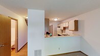 This two-story home offers a well-organized layout designed for comfortable everyday living. The kitchen is thoughtfully equipped with ample oak-trimmed cabinetry, light-toned countertops, a double sink, and a full suite of appliances including a coil-burner range, built-in microwave, dishwasher, and refrigerator. Light hardwood-style flooring runs through the kitchen and main-level living areas, lending a warm, cohesive look. A pass-through counter connects the kitchen to the adjacent living space, enhancing the open feel of the main floor.

The living room is a comfortable gathering space featuring plush carpeting, a wood-burning fireplace, and a sliding glass door that opens to an outdoor patio and views of lush greenery — allowing natural light to fill the room throughout the day.

Upstairs, the bedrooms are carpeted and bright, each benefiting from natural light through blinds-fitted windows. The primary bedroom features vaulted ceiling details and an expansive wall of built-in closets providing generous storage. Additional bedrooms include closets and ceiling fan fixtures. The full bathroom presents a wide double-sink vanity with oak-accented cabinetry, a large mirror, and a textured ceiling — offering a clean, functional space.