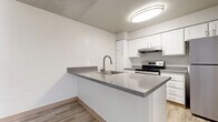 This single-floor unit offers a clean, modern aesthetic throughout, with thoughtful finishes and a functional layout evident from the 3D floor plan. The kitchen serves as a central highlight, featuring a peninsula with stone-speckled quartz countertops, an undermount stainless steel sink with a pull-down faucet, crisp white cabinetry with contemporary hardware, and a full suite of stainless steel appliances including an electric range and refrigerator. Light wood-look flooring runs through the kitchen and living areas, contributing to a bright and cohesive feel. The living room benefits from a large sliding glass door that fills the space with natural light and provides direct views to the outdoors. The entry area transitions seamlessly into the main living space, also finished with the same wood-look flooring. The bedrooms are carpeted for comfort, offering neutral tones and ample natural light through blinds-fitted windows. One bedroom features a wide sliding-door closet, providing generous storage. The bathroom is outfitted with a full-size soaking tub and shower combination, finished with clean white tile surround, wood-look flooring, and brushed nickel fixtures, completing this well-maintained and move-in ready space.