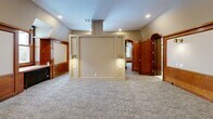 Located at 888 Delaware Ave in Buffalo, NY, this single-floor space offers three bedrooms and one bathroom, showcasing a compelling mix of historic character and contemporary finishes. The expansive primary bedroom is a standout feature, distinguished by rich oak wood paneling, a classic brick fireplace with a detailed wood mantel, built-in cabinetry, and original cast-iron radiators that speak to the building's storied past. Arched wood doorways with ornate detailing provide graceful transitions between rooms, reinforcing the space's architectural heritage. Recessed lighting and warm wall sconces illuminate the neutral-toned, carpeted floors throughout, creating a welcoming ambiance. Additional bedrooms offer more intimate settings, one featuring angled ceilings and a window that invites natural light, while a curved hallway with rich wood baseboards connects the rooms seamlessly. The bathroom is well-appointed with marble-style tile flooring, a glass-enclosed shower with tile surround, and clean, modern fixtures complemented by warm wood trim. Overall, this space masterfully preserves its historic Buffalo roots while providing functional, comfortable living accommodations.