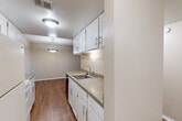 Located at 3030 E Fountain Blvd in Colorado Springs, CO, this single-floor, 2-bedroom, 3-bathroom residence offers a practical and well-organized layout. The kitchen features white cabinetry, a stainless steel sink, granite-style countertops, and warm hardwood-style flooring, flowing naturally into the adjoining dining area illuminated by a pendant light fixture. The open-plan living and dining areas transition between carpet and hardwood-style flooring, creating distinct yet connected zones beneath textured ceilings. The spacious primary bedroom offers generous proportions, plush carpeting, a built-in closet with bifold doors, and a window with vertical blinds allowing natural light. The second bedroom is similarly carpeted with its own window and access to the hallway. Three bathrooms are distributed throughout the unit, each featuring white vanity cabinetry, oval mirrors, granite-style countertops, and clean, understated finishes. One bathroom includes a tiled tub/shower surround in classic white. Additional storage is provided by four closets spread across the floor plan, complemented by a dedicated utility room. Neutral wall tones, white trim, and consistent finishes lend a cohesive aesthetic throughout the entire space.