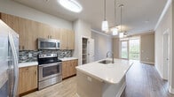 Located at 510 N Wilmington St in Raleigh, NC, this single-floor, one-bedroom, one-bathroom residence offers a thoughtfully designed layout with contemporary finishes throughout. The open-concept living, dining, and kitchen area serves as the heart of the home, featuring light wood-toned cabinetry, a mosaic tile backsplash, and a full suite of stainless steel appliances including a refrigerator, range, and built-in microwave. A central kitchen island with a white quartz countertop and undermount sink provides additional prep space and serves as a natural gathering point. Pendant lighting overhead adds a modern touch, while a dedicated pantry offers convenient storage. The living area is finished with wood-style flooring and crown molding, and a ceiling fan with access to a private balcony brings in natural light. The spacious bedroom features plush carpeting, a ceiling fan, and a large window with outdoor views. Multiple closets provide generous storage throughout. The bathroom is finished with tile flooring, a wood-toned vanity with a white countertop, a large mirror, and a full soaking tub and shower combination with arched tile surround. A separate laundry area and utility room complete this well-organized residence.