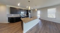 Located at 401 S Coit in McKinney, Texas, this single-story residence offers a thoughtfully designed open-concept layout with modern finishes throughout. The kitchen serves as the heart of the home, showcasing rich dark cabinetry, granite countertops, a subway tile backsplash, and a full suite of stainless steel appliances including an electric range, microwave, and refrigerator. A central island with an undermount sink and pendant lighting above adds both functionality and visual appeal. The kitchen flows seamlessly into a generous living area finished with wood-look flooring, multiple windows that invite natural light, and a ceiling fan for year-round comfort. A glass door provides direct outdoor access from the living space. The bedrooms are carpeted for warmth and comfort, each featuring windows with blinds and ceiling fans. The primary bathroom is well-appointed with a dual-sink granite vanity, dark cabinetry, wood-look flooring, a walk-in closet, and a soaking tub surrounded by large-format tile. An additional bathroom provides a tub-shower combination with the same quality tile work. Throughout the residence, clean neutral walls, recessed lighting, and consistent finishes create a cohesive and contemporary ambiance.