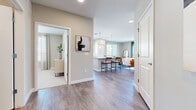 This thoughtfully designed single-floor residence offers a seamless open-concept layout that connects the main living areas with ease and functionality. Wide-plank wood-look flooring flows throughout the common spaces, lending warmth and continuity to the interior.

The kitchen serves as a central hub, showcasing white shaker cabinetry, granite countertops, stainless steel appliances, and a generous island with bar seating. Pendant lighting above the island adds a refined touch, while abundant natural light pours in through multiple windows overlooking the surrounding neighborhood.

The living room is bright and welcoming, anchored by large windows dressed with teal curtains that frame outdoor views. The space comfortably accommodates a full seating arrangement and flows naturally into a dedicated dining area.

The primary bedroom is a serene retreat, featuring plush carpeting, generous proportions, and access to a well-designed en-suite bathroom. The bathroom includes a granite-topped vanity with white cabinetry and a walk-in shower with subway tile surround, alongside a spacious walk-in closet with built-in shelving. A secondary bedroom offers ample closet space and soft carpeting, ideal as a guest room or home office. The hallway connects all areas efficiently, completing a cohesive and comfortable living environment.
