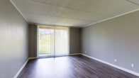 Located at 3316 Foxboro Dr in Woodridge, IL, this single-floor unit offers a well-organized layout with a cohesive, modern aesthetic throughout. The open living area is a standout feature, showcasing rich, dark hardwood-style flooring and neutral gray walls that create a clean, contemporary look. A large sliding glass door flanked by vertical blinds floods the space with natural light and provides pleasant views of the surrounding greenery, extending the visual depth of the room. The kitchen is designed for functionality and style, featuring rich dark-brown cabinetry, white countertops, and black appliances including a refrigerator, electric range, and under-cabinet range hood. A peninsula counter connects the kitchen to the living area, creating an open, efficient flow between the two spaces. The bedroom offers plush carpeting underfoot, soft gray walls, and a spacious closet with built-in rod storage, providing ample organization. The bathroom is clean and well-appointed, with a full soaking tub and shower combo featuring white tile surround, brushed nickel fixtures, and wood-look flooring that ties the space together. Throughout the unit, textured ceilings and crisp white trim add a classic finishing touch to this well-maintained Woodridge residence.