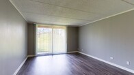 Located at 3316 Foxboro Dr in Woodridge, IL, this single-floor unit offers a well-organized layout with a cohesive, modern aesthetic throughout. The open living area is a standout feature, showcasing rich, dark hardwood-style flooring and neutral gray walls that create a clean, contemporary look. A large sliding glass door flanked by vertical blinds floods the space with natural light and provides pleasant views of the surrounding greenery, extending the visual depth of the room. The kitchen is designed for functionality and style, featuring rich dark-brown cabinetry, white countertops, and black appliances including a refrigerator, electric range, and under-cabinet range hood. A peninsula counter connects the kitchen to the living area, creating an open, efficient flow between the two spaces. The bedroom offers plush carpeting underfoot, soft gray walls, and a spacious closet with built-in rod storage, providing ample organization. The bathroom is clean and well-appointed, with a full soaking tub and shower combo featuring white tile surround, brushed nickel fixtures, and wood-look flooring that ties the space together. Throughout the unit, textured ceilings and crisp white trim add a classic finishing touch to this well-maintained Woodridge residence.