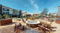 Located at 11576 Pearland Pkwy in Houston, TX 77075, this amenity space offers a thoughtfully designed environment for relaxation and entertainment. The interior opens into a spacious lounge area featuring plush sectional sofas accented with bold yellow and patterned throw pillows, set atop patterned carpeting. A warm, illuminated tray ceiling with recessed lighting adds architectural depth, while large windows invite abundant natural light and views of the surrounding area.

Adjacent to the lounge is a dedicated screening room, designed for an immersive media experience. Deep, wraparound sectional seating fills the room, complemented by floor-to-ceiling blackout drapery that ensures optimal viewing conditions. A curated gallery wall of framed artwork adds a sophisticated touch, and a wall-mounted flat-screen TV with streaming capabilities anchors the entertainment setup. Warm cove lighting along the ceiling creates a cinematic ambiance.

The interior connects seamlessly via modern sliding doors to a bright main lounge corridor featuring wood-paneled walls and granite ledges. Outdoors, the space transforms into a vibrant social hub centered around a large circular fire pit surrounded by Adirondack chairs set on a gravel plaza. Overhead string lights, shaded gazebos, raised planters, and picnic tables complete the outdoor gathering area, all set beneath an open Houston sky.