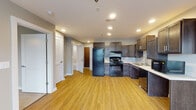 This single-floor residence in Lexington, Kentucky, offers a thoughtfully designed layout that balances functionality and comfort throughout. The kitchen serves as a central highlight, outfitted with rich dark-stained cabinetry, light countertops, black appliances including a full-size refrigerator, gas range, dishwasher, and microwave, all set atop warm luxury vinyl plank flooring. Recessed lighting illuminates the space effectively, creating a bright and practical cooking environment. The open flow from the kitchen leads into a generously sized living area, also finished with the same warm-toned flooring and large windows that invite natural light. The bedrooms are carpeted in a neutral tone, each featuring ceiling fans with lighting and windows with blinds for privacy. The primary bedroom includes dual closets with wire shelving, offering substantial storage capacity. The bathroom is designed with accessibility in mind, featuring grab bars, a walk-in shower, and a separate soaking tub, all finished with coordinating hard-surface flooring. Neutral wall tones throughout the space create a cohesive and versatile backdrop, while consistent trim and door detailing lend a clean, polished aesthetic. This residence combines practical design with comfortable living in a convenient Lexington location.