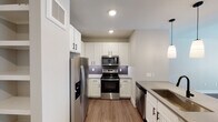Located in Austin's vibrant 78702 neighborhood, this single-floor residence showcases a thoughtfully designed open-concept layout connecting the kitchen and living areas. The kitchen is a standout feature, equipped with stainless steel appliances including a French door refrigerator, electric range, built-in microwave, and dishwasher. White shaker-style cabinetry with matte black hardware pairs with a subway tile backsplash and quartz countertops. A central island with an undermount sink and matte black faucet serves as both a prep station and gathering point, illuminated by a trio of pendant lights that carry the eye toward the open living space beyond.

The living area benefits from natural light streaming through French doors and windows, accented by a ceiling fan overhead. Wood-style flooring flows throughout the main areas, transitioning to plush carpet in the bedroom, which features a ceiling fan and blinds for comfort and privacy. The bathroom is generously proportioned, offering a dual-sink vanity with quartz countertops, matte black fixtures, a large mirror, and a soaking tub with vertically tiled surround. Light tile flooring and ample storage cabinetry complete this clean, contemporary space.